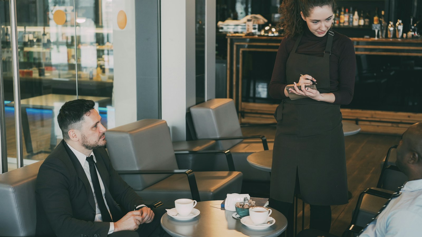Waitress taking an order from two guests at a café table
