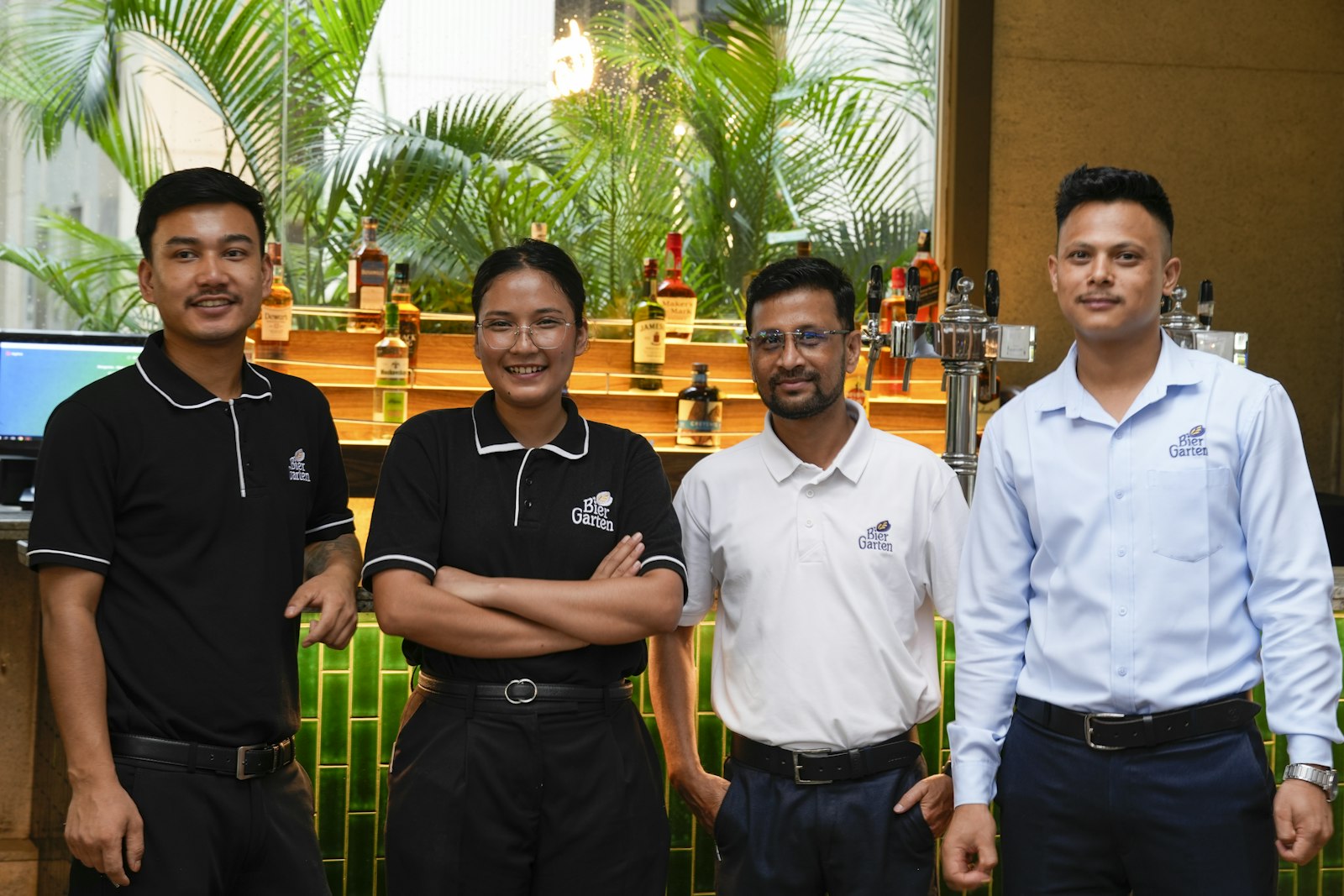 Four smiling hospitality staff members standing in front of a bar