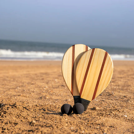 Outdoor wooden frescobol tennis set by XD Collection featuring two polished wooden paddles and a matching ball on a natural background.