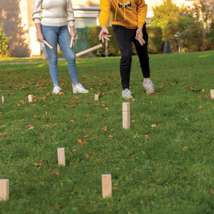 Outdoor wooden Kubb set by XD Collection with game pieces and throwing batons on a grassy surface.